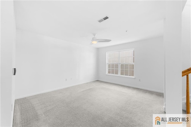 empty room featuring carpet floors, baseboards, visible vents, and a ceiling fan