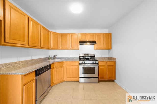 kitchen with light tile patterned floors, stainless steel appliances, a sink, light stone countertops, and under cabinet range hood