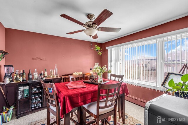 carpeted dining space with bar, ceiling fan, and a baseboard heating unit