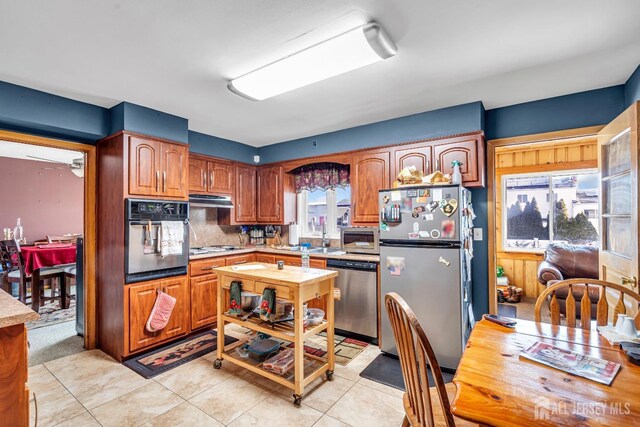 kitchen featuring appliances with stainless steel finishes, backsplash, a wealth of natural light, and light tile patterned flooring