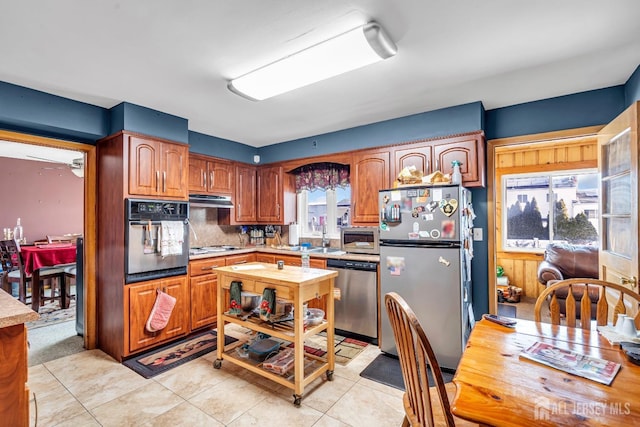 72-74 Sabo St, Carteret, NJ 07008 - kitchen featuring stainless steel appliances, light countertops, light tile patterned floors, under cabinet range hood, and brown cabinetry