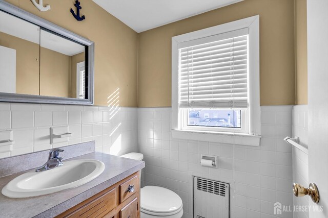 bathroom with radiator, vanity, tile walls, and toilet