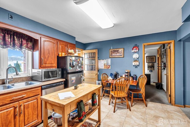 kitchen with light tile patterned flooring, appliances with stainless steel finishes, and sink