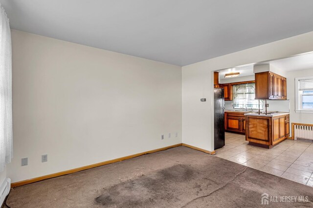 kitchen with light colored carpet, black fridge, radiator heating unit, and a baseboard radiator