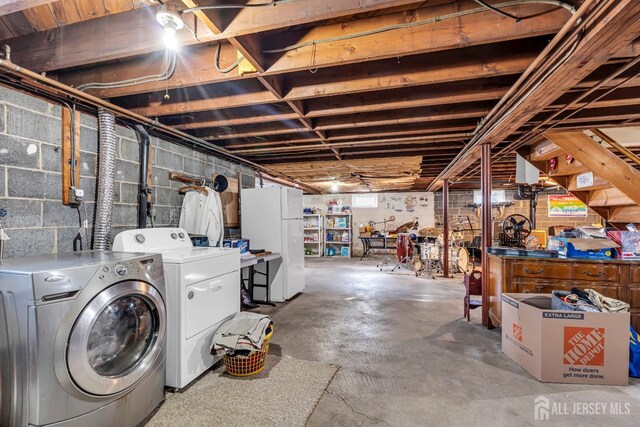 basement featuring washer and clothes dryer and white refrigerator