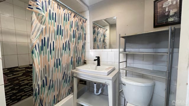 bathroom with sink, tile walls, and toilet