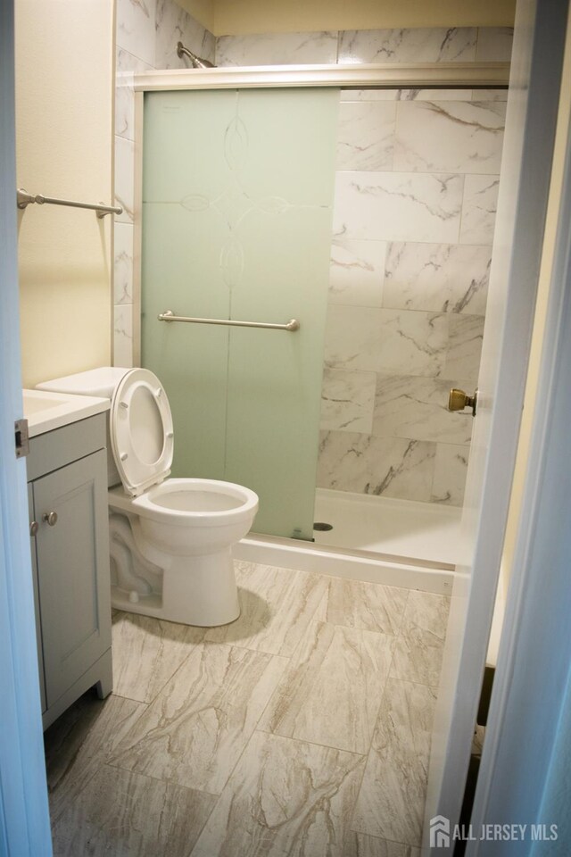 bathroom with walk in shower, vanity, and toilet