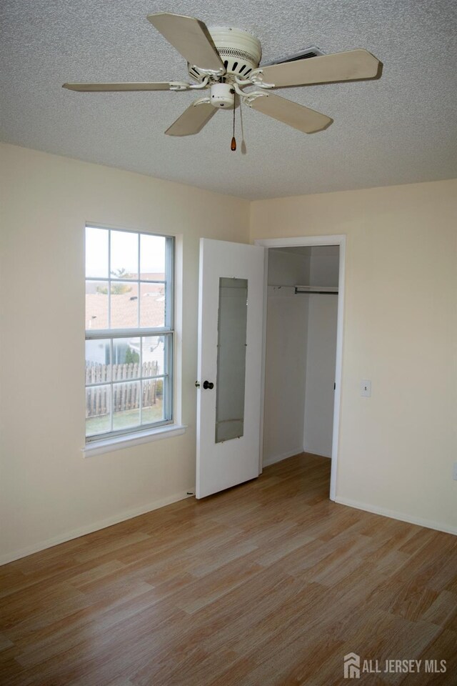 unfurnished bedroom featuring ceiling fan, light hardwood / wood-style flooring, a closet, and a textured ceiling