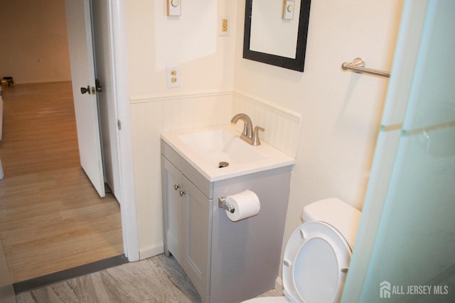 bathroom with toilet, wood-type flooring, and vanity