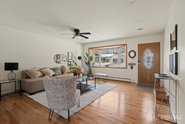 living room with crown molding, baseboard heating, light wood-style floors, a ceiling fan, and visible vents