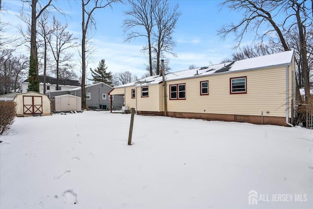 snow covered house featuring a storage shed