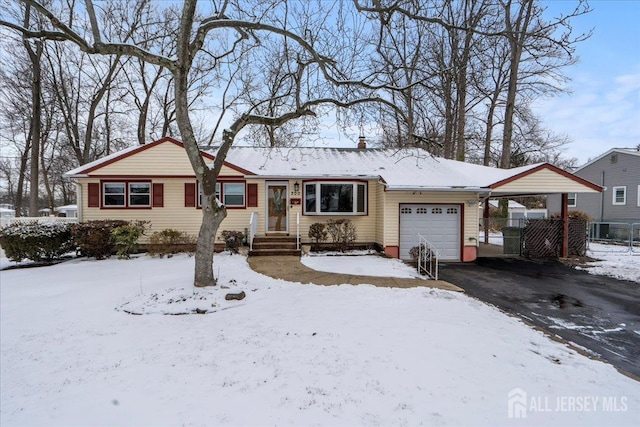 ranch-style home featuring a carport, fence, a garage, and aphalt driveway