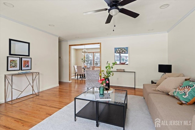 living area with ornamental molding, ceiling fan with notable chandelier, and wood finished floors