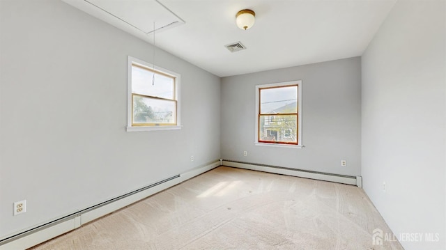 unfurnished room with carpet floors, attic access, a baseboard radiator, and visible vents