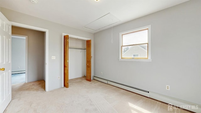 unfurnished bedroom with light carpet, baseboard heating, attic access, and a closet