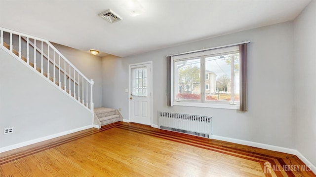 entrance foyer with visible vents, baseboards, radiator, and stairs