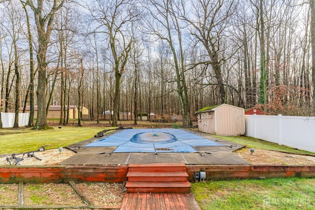 view of pool featuring a storage shed, a fenced backyard, a lawn, and an outdoor structure