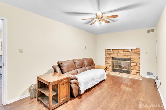 living area featuring visible vents, wood finished floors, and a stone fireplace