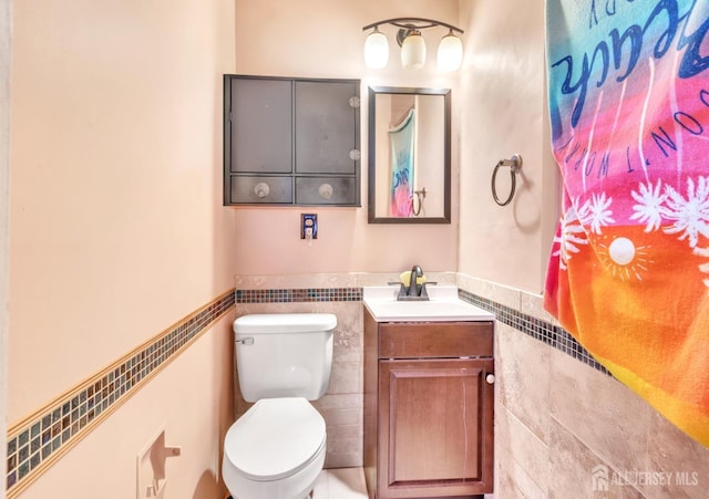 bathroom with tile walls, toilet, and vanity