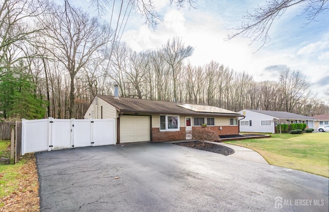 view of front of house featuring a garage, brick siding, driveway, a gate, and a front yard