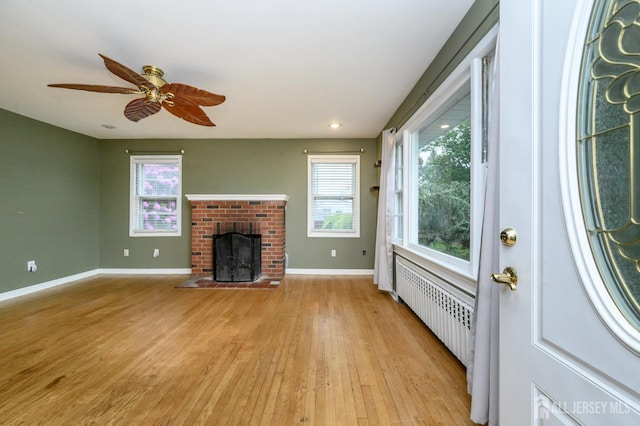 4 Ashwood Pl, North Brunswick, NJ 08902 - unfurnished living room with radiator, light wood-style flooring, baseboards, a brick fireplace, and a ceiling fan