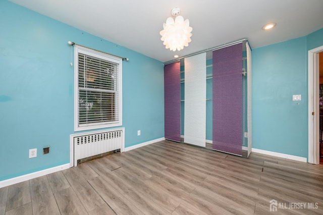4 Ashwood Pl, North Brunswick, NJ 08902 - spare room featuring radiator, wood finished floors, baseboards, recessed lighting, and a chandelier