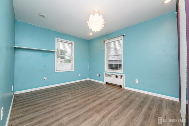 4 Ashwood Pl, North Brunswick, NJ 08902 - unfurnished room with radiator heating unit, wood finished floors, a chandelier, and baseboards