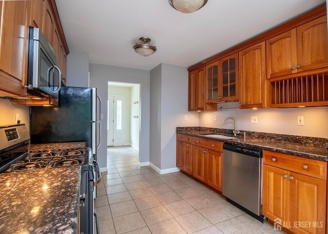 33 Timber Rd, Edison, NJ 08820 - kitchen with appliances with stainless steel finishes, brown cabinetry, light tile patterned flooring, dark stone counters, and glass insert cabinets