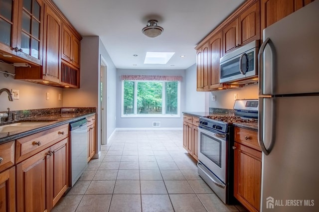 33 Timber Rd, Edison, NJ 08820 - kitchen featuring appliances with stainless steel finishes, a skylight, glass insert cabinets, dark stone countertops, and light tile patterned floors