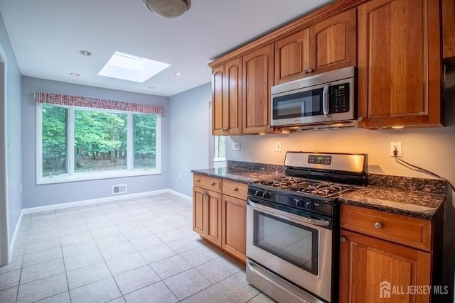 33 Timber Rd, Edison, NJ 08820 - kitchen featuring appliances with stainless steel finishes, a skylight, dark stone countertops, brown cabinets, and recessed lighting