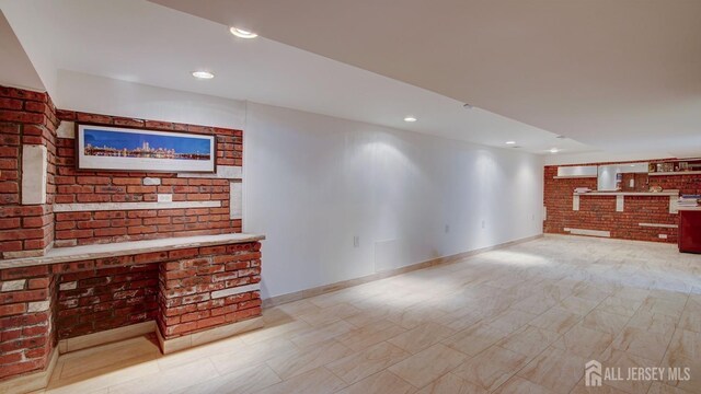 living room featuring recessed lighting, baseboards, and brick wall