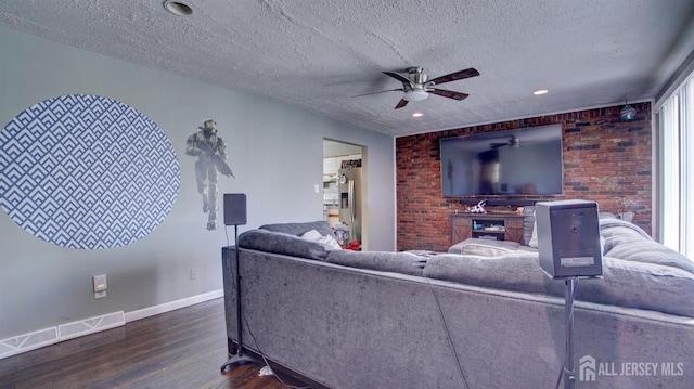 living room with a textured ceiling, wood finished floors, visible vents, and baseboards