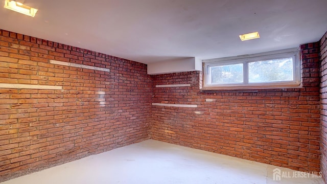 spare room featuring brick wall and concrete floors