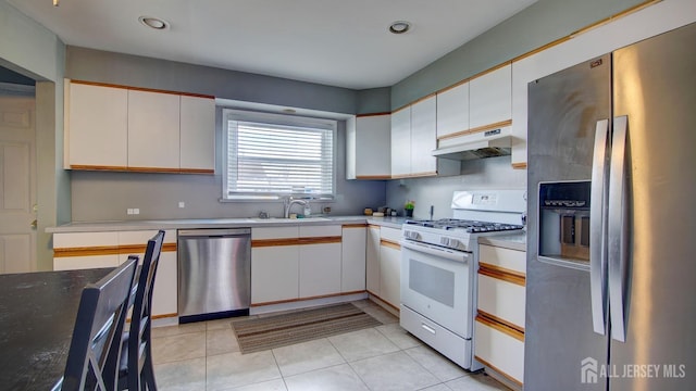 kitchen featuring under cabinet range hood, light tile patterned floors, appliances with stainless steel finishes, white cabinets, and a sink