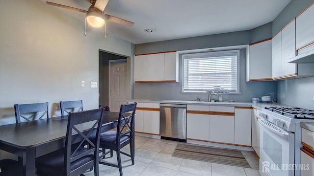 kitchen featuring a sink, stainless steel dishwasher, white cabinetry, light countertops, and white gas range