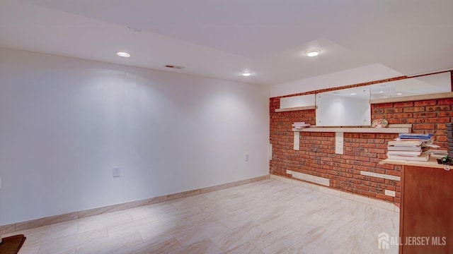 living area with visible vents, baseboards, and brick wall