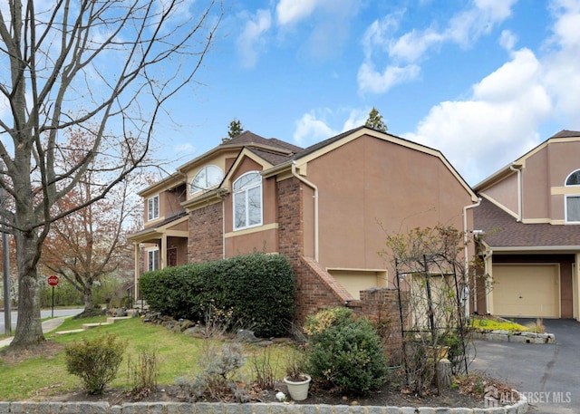 view of front of home featuring stucco siding, asphalt driveway, and a garage