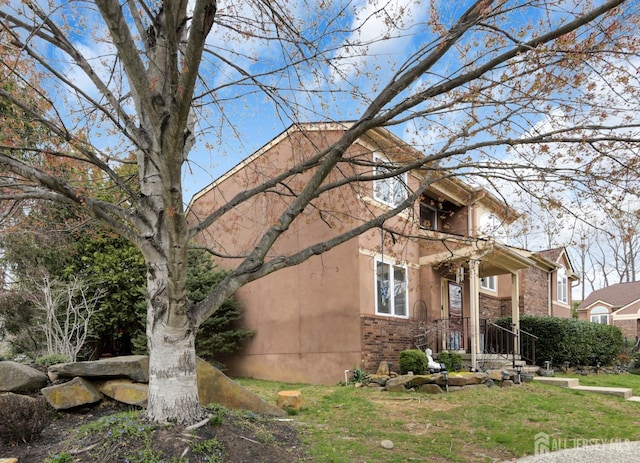view of side of home with stucco siding, a yard, and brick siding