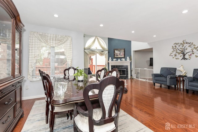 dining room featuring wood finished floors, recessed lighting, a tile fireplace, and baseboards