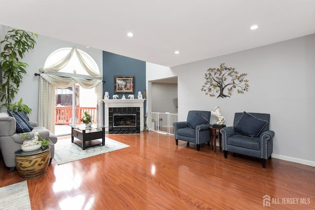 living area with wood finished floors, a fireplace, recessed lighting, and baseboards