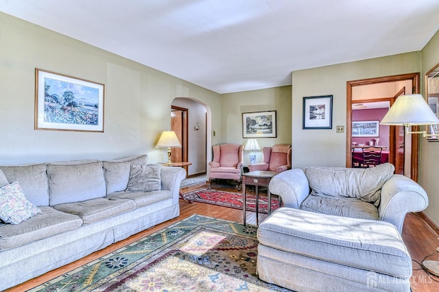 living room with arched walkways and wood finished floors