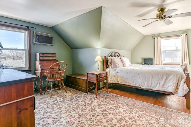 bedroom with lofted ceiling, wood finished floors, a ceiling fan, and a wall unit AC