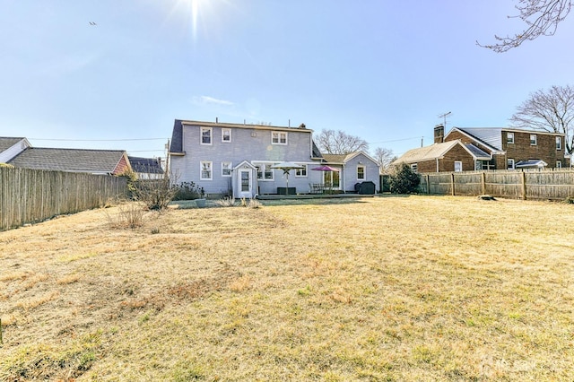 rear view of property featuring a lawn and a fenced backyard