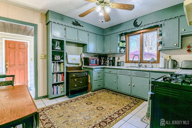 kitchen featuring open shelves, a sink, light tile patterned floors, black range with gas stovetop, and tile counters