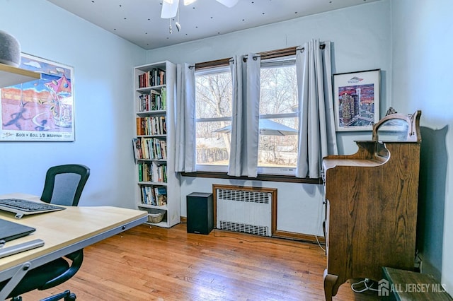 office space featuring wood-type flooring, ceiling fan, and radiator heating unit