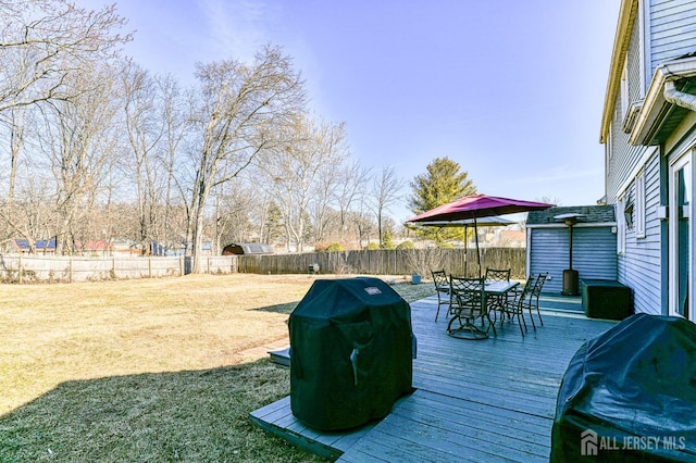 deck featuring grilling area, a fenced backyard, a yard, and outdoor dining space