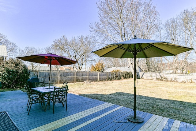 wooden deck featuring outdoor dining area, a fenced backyard, and a lawn