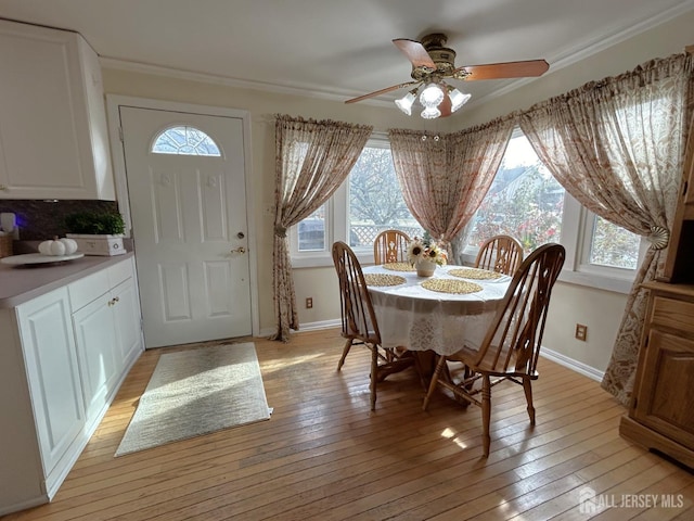 dining space featuring light wood-style floors, crown molding, baseboards, and ceiling fan