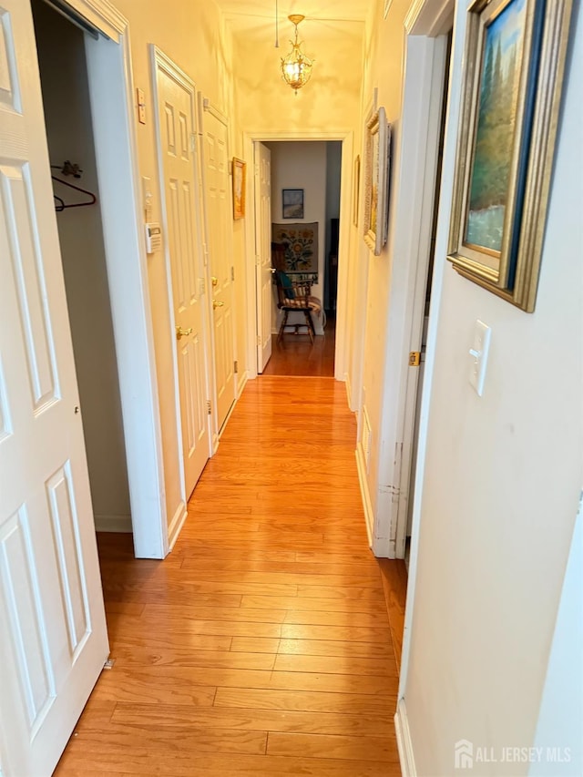 corridor with light wood-style flooring and baseboards