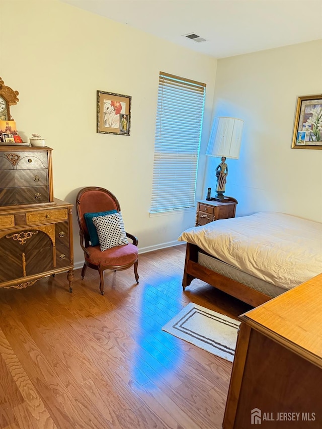 bedroom featuring visible vents, baseboards, and wood finished floors